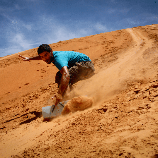 Go sandboarding down red dunes of the Pinnacles Desert