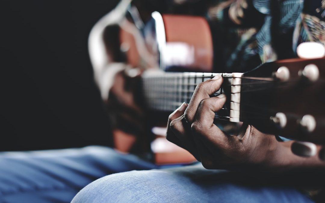 person playing a brown guitar