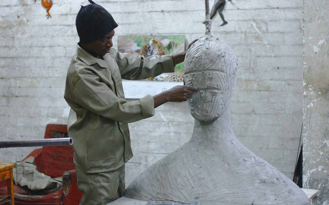 A sculptor works in his studio sculpting a large white body and head