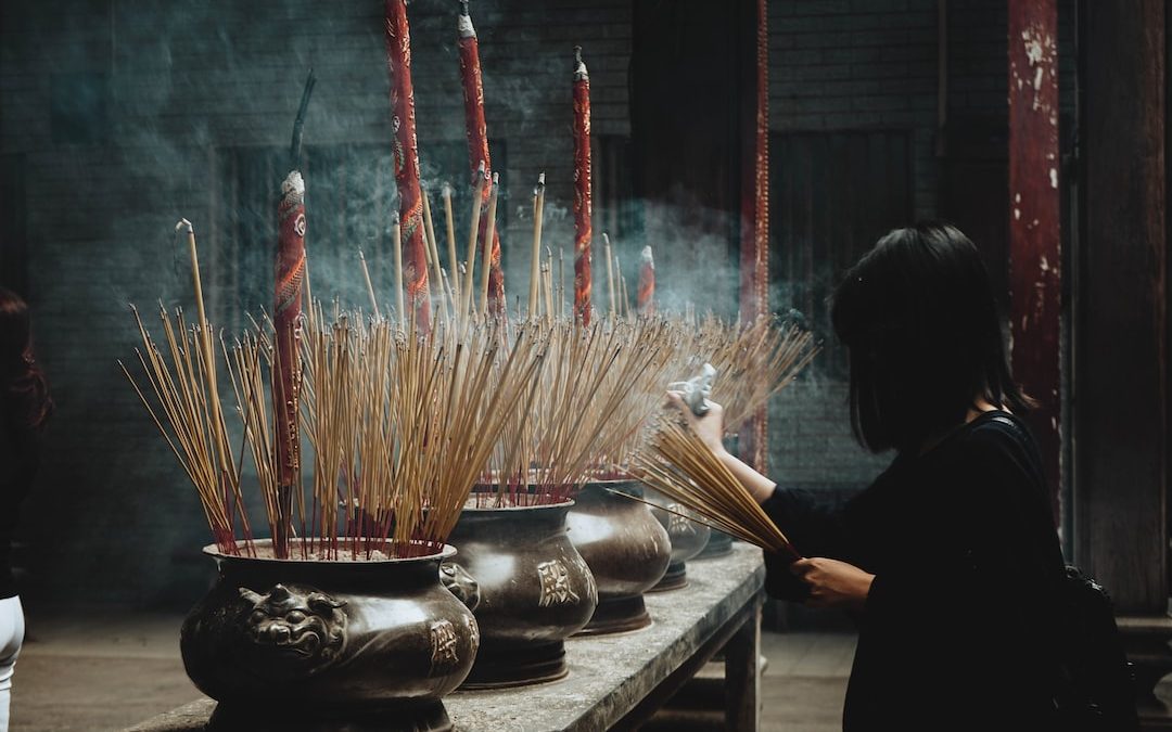 woman putting incense sticks on pot