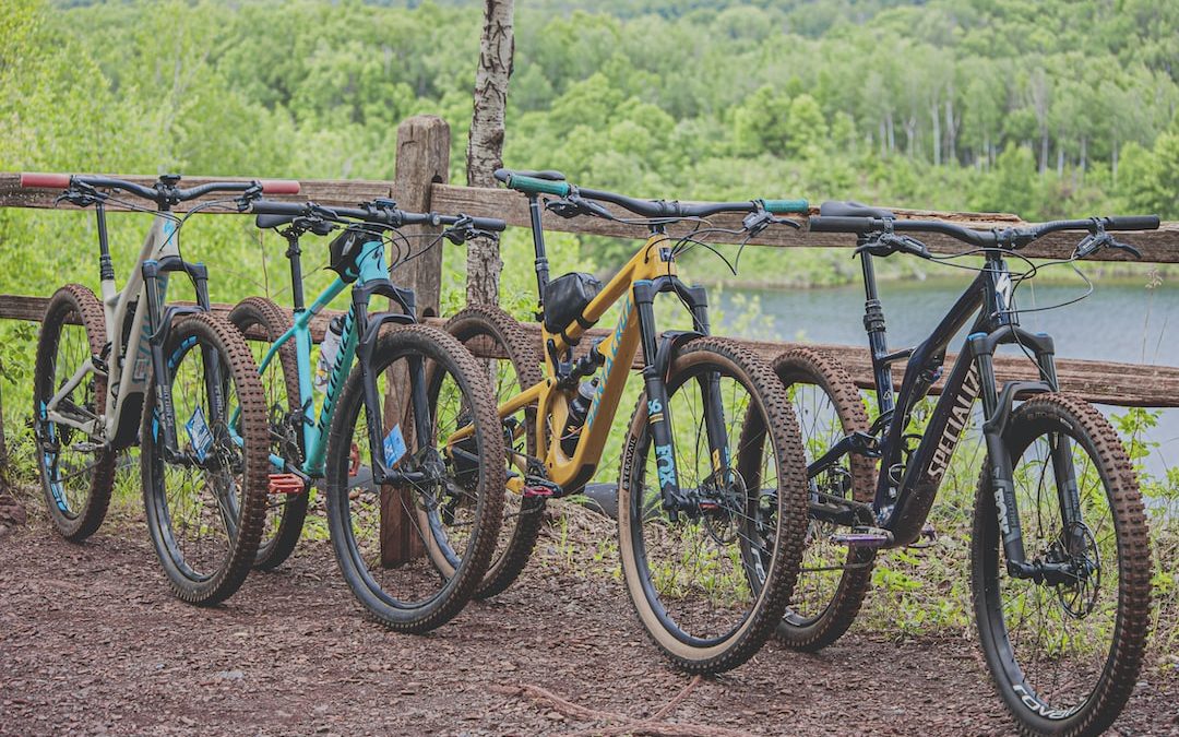 four multicolored mountain bikes parked beside brown wooden railing