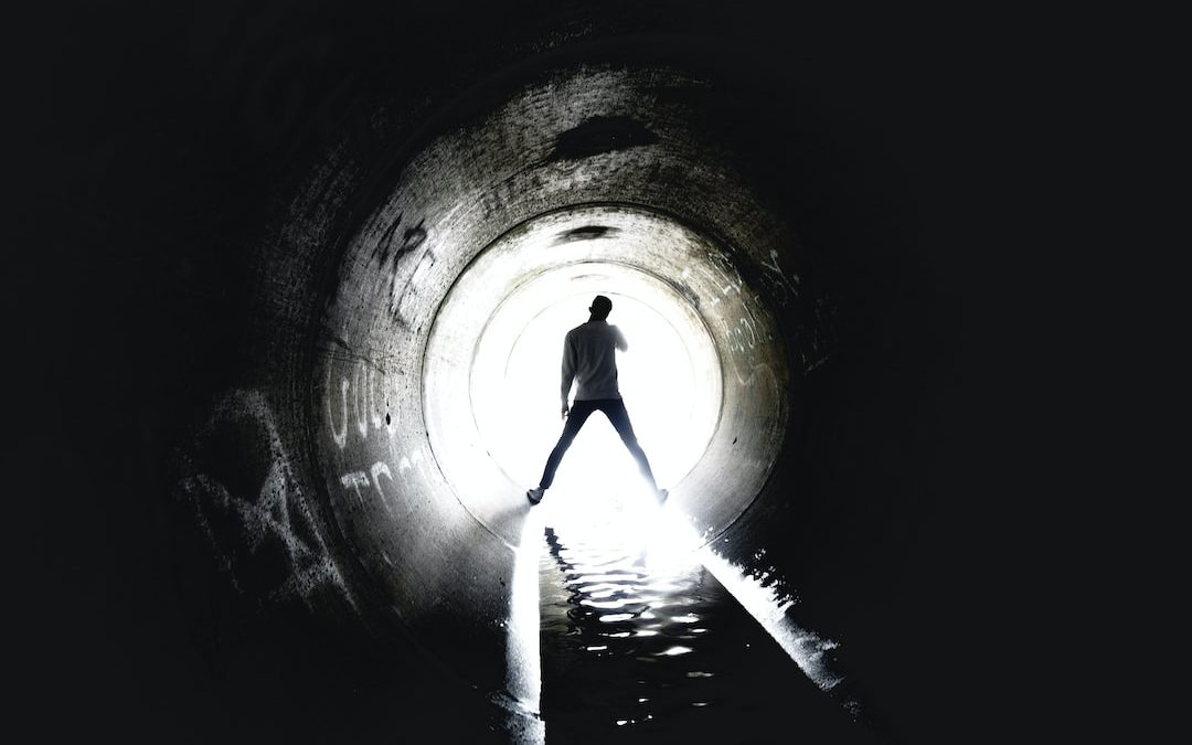 person standing inside sewer tunnel