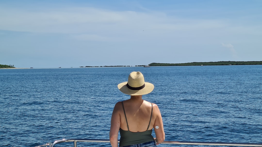 woman in brown sun hat and brown tank top sitting on boat during daytime