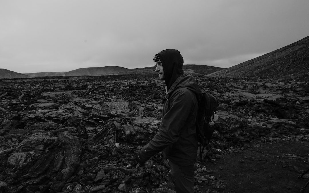 a man with a backpack walking through a rocky field