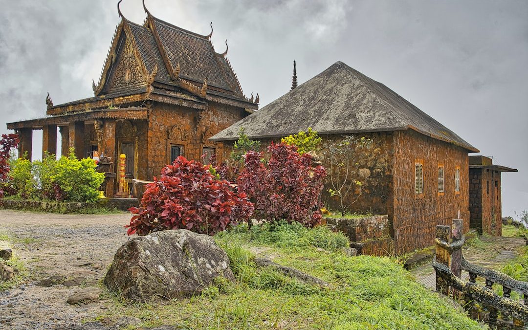 a stone building with a thatched roof next to a tree