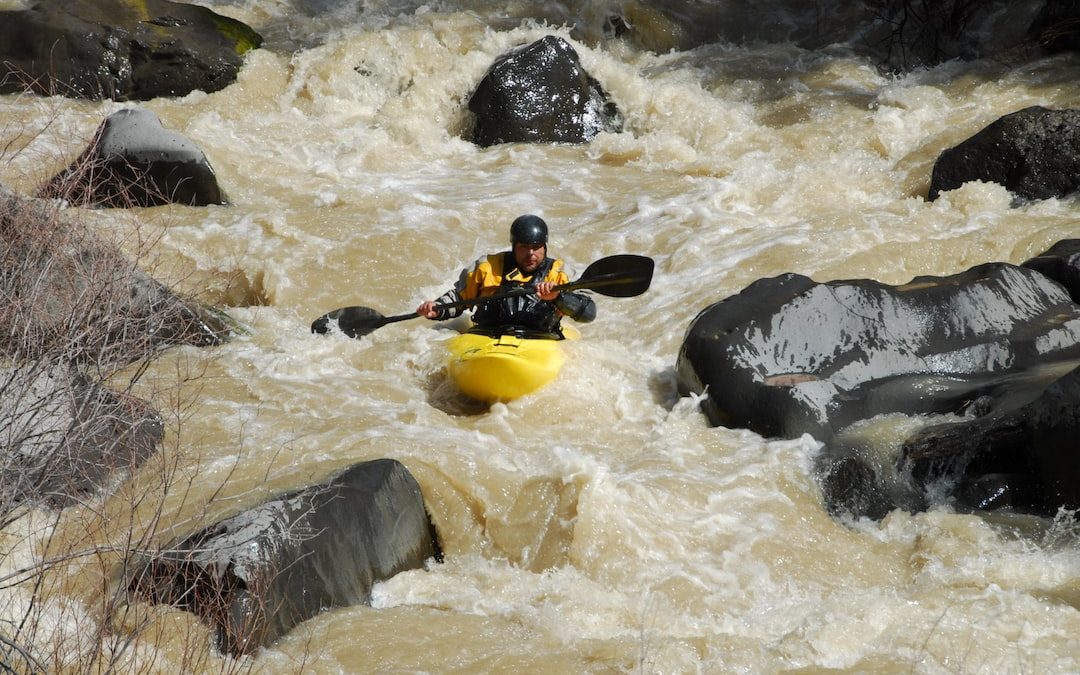 man in black and yellow jacket riding yellow kayak on river during daytime