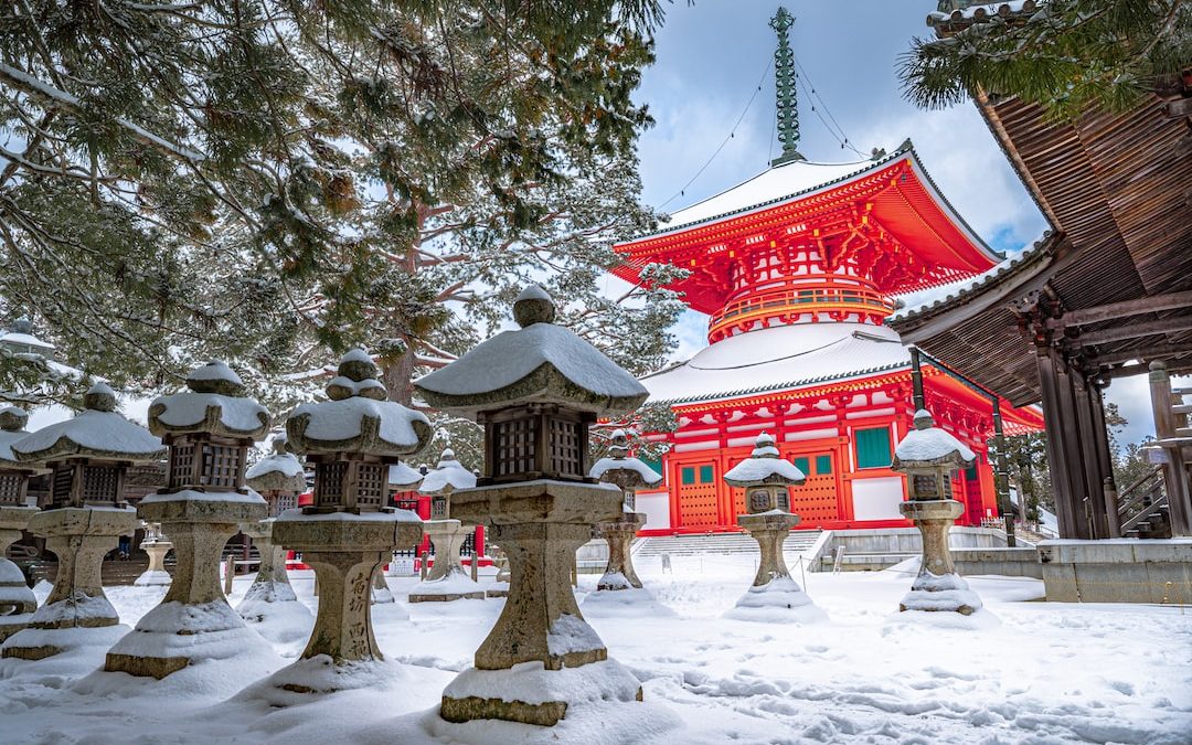 red and white temple surrounded by trees covered with snow