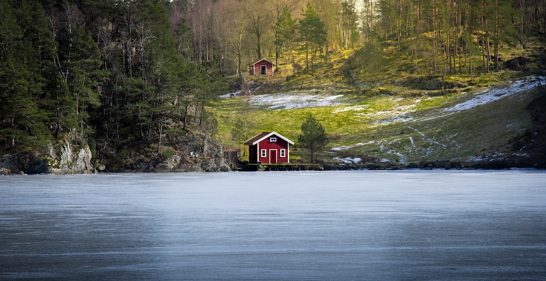 red house beside body of water surrounded by trees
