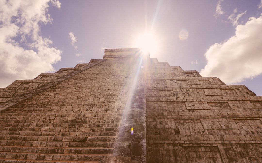 the sun shines brightly through the clouds above a pyramid