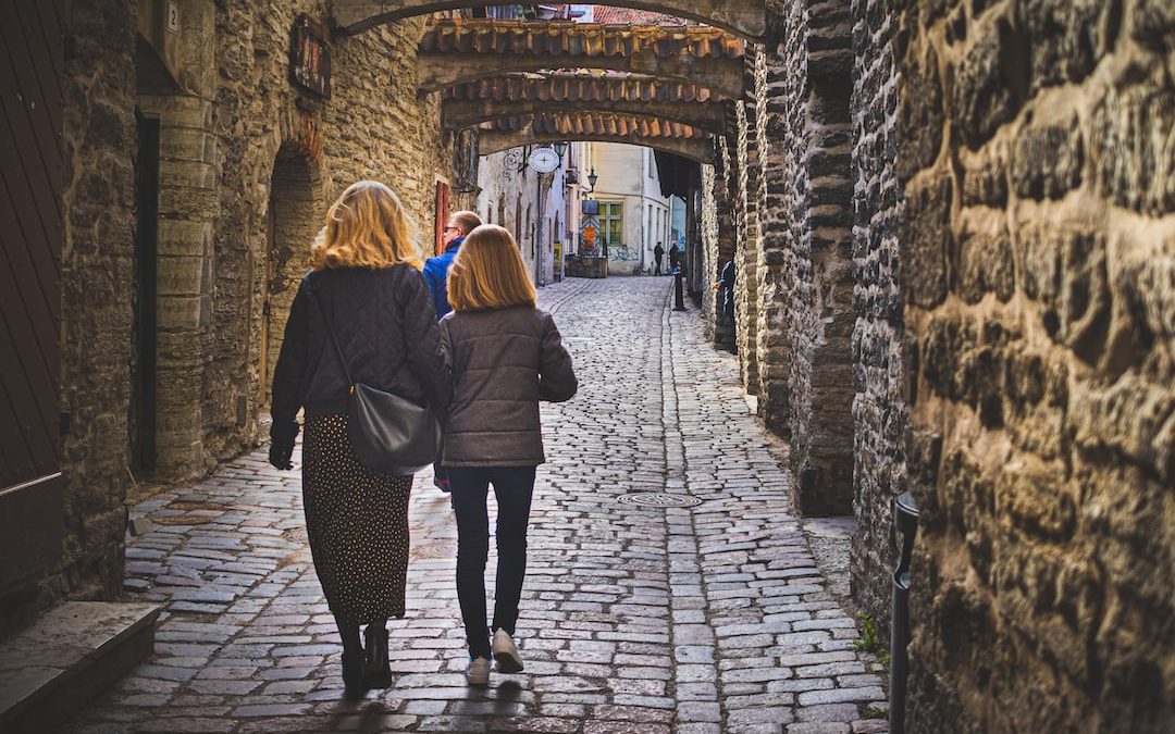 a couple of women walking down a stone street