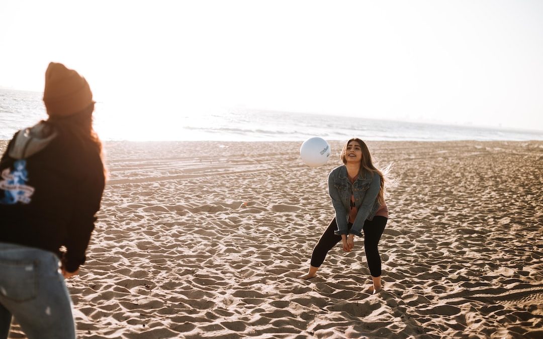 two women playing volleyball on seashore