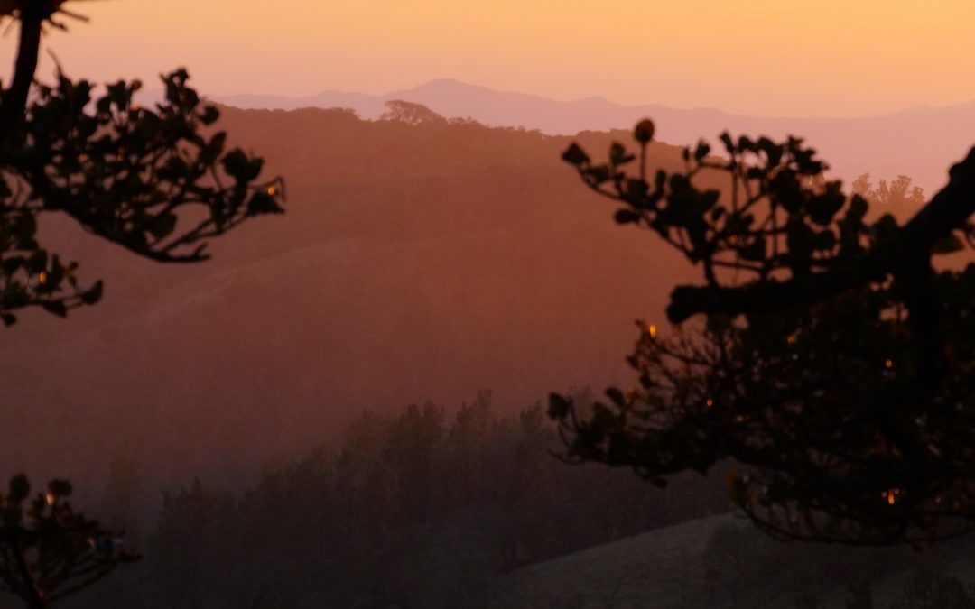 the sun is setting over a mountain range