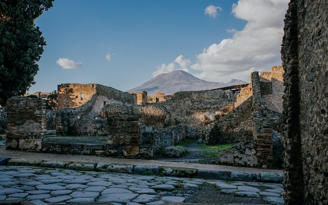 a stone walkway with a stone wall and a mountain in the background