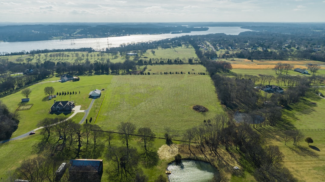 an aerial view of a large field with a lake in the background