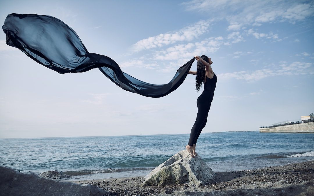 a woman standing on top of a rock near the ocean