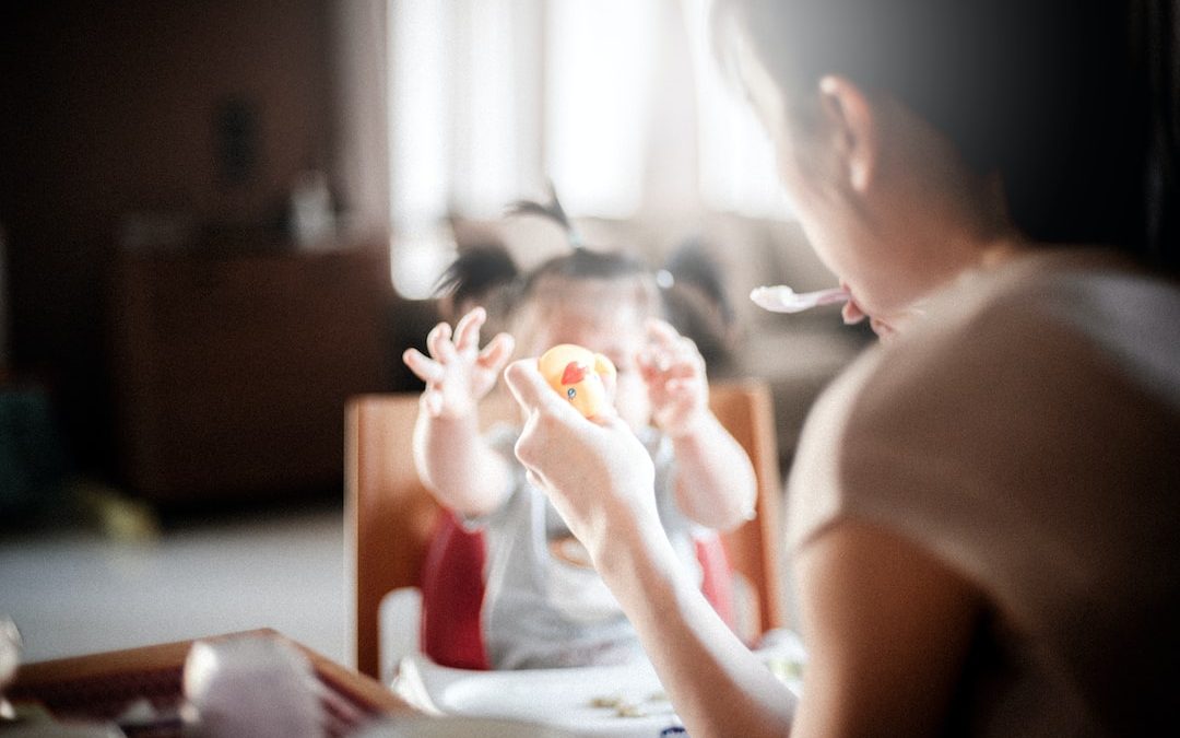 selective focus photography of woman feeding baby