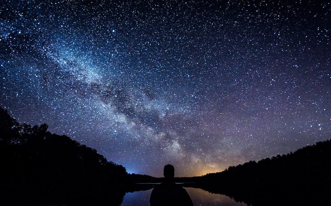 silhouette of person standing under starry sky