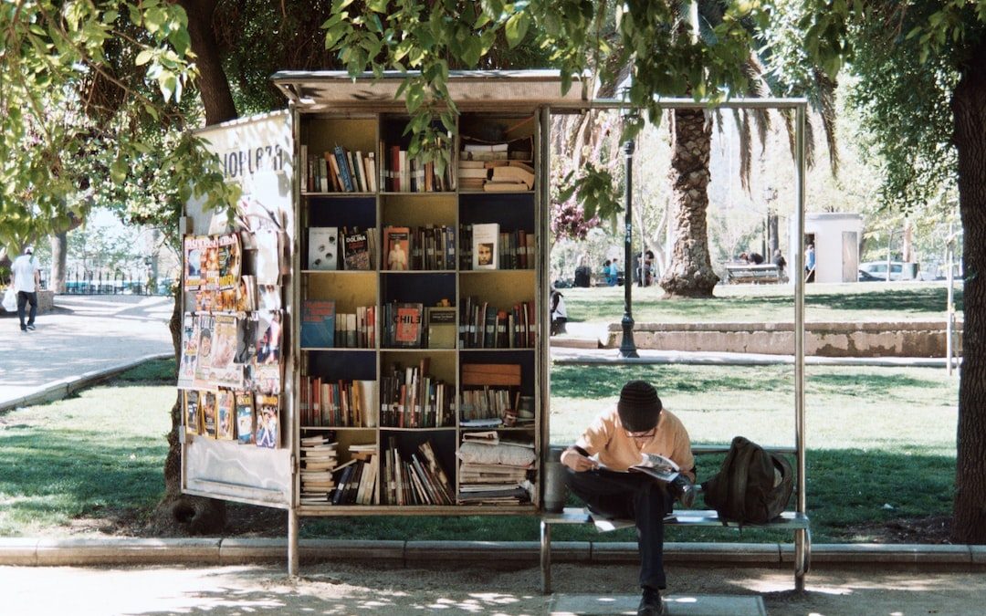 boy sitting on bench beside bookshelf