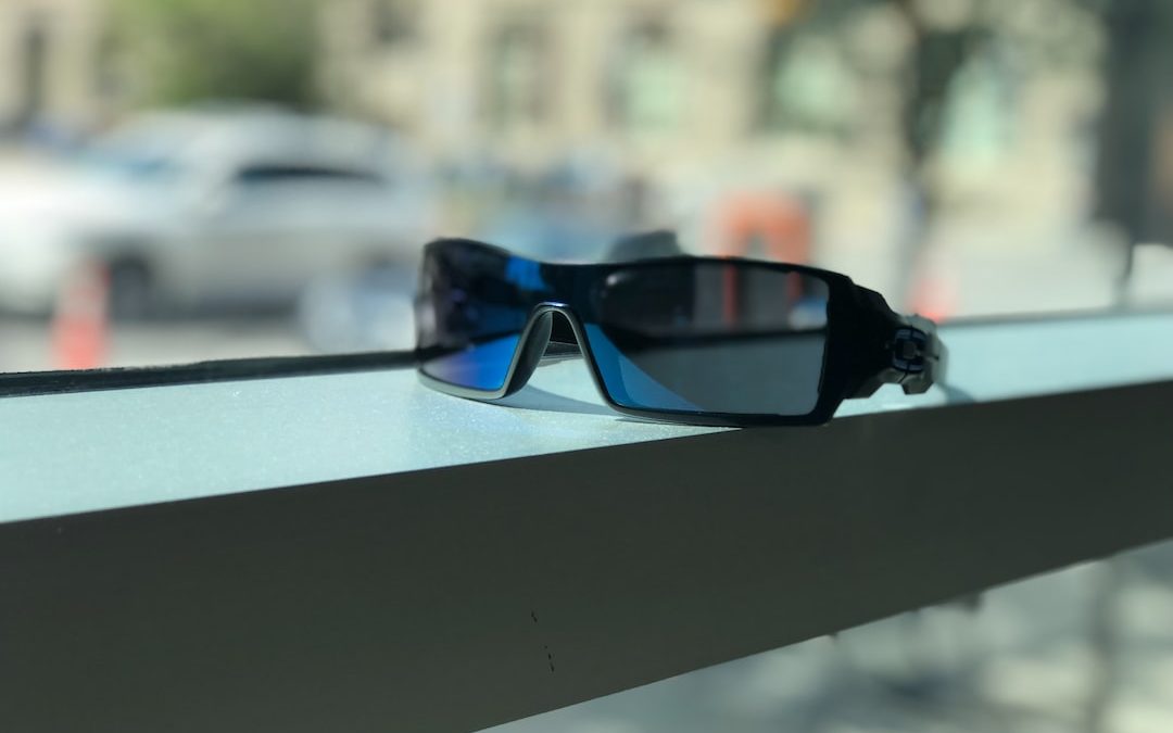 black framed blue lens sunglasses near window