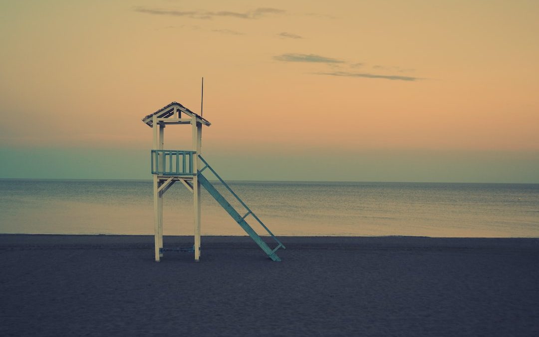 white wooden lifeguard station near seashore at golden hour