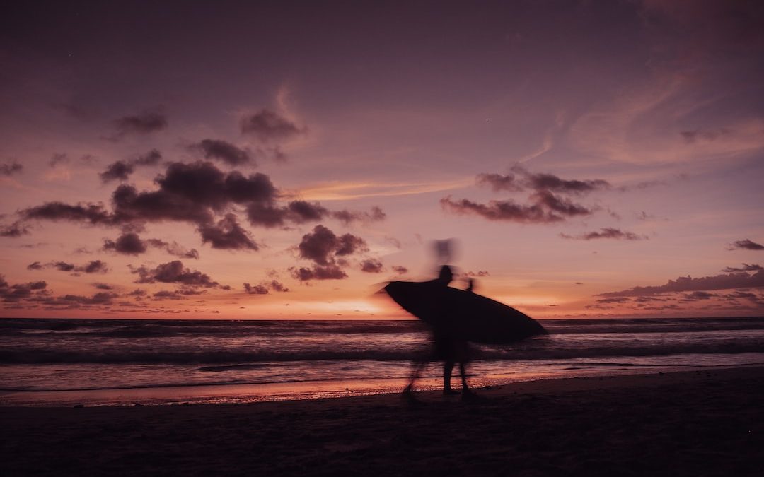 a person standing on a beach holding a surfboard