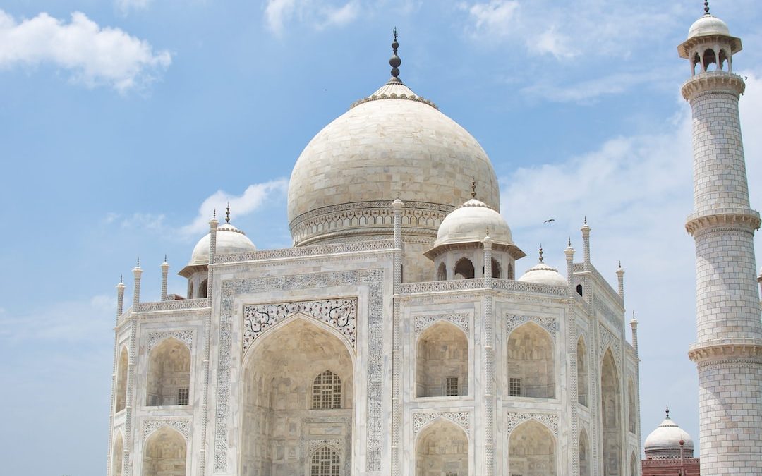 a large white building with domed roofs with Taj Mahal in the background