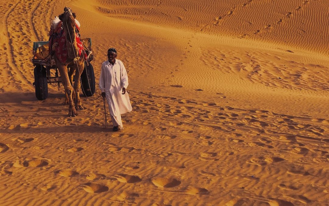man and woman walking on desert during daytime