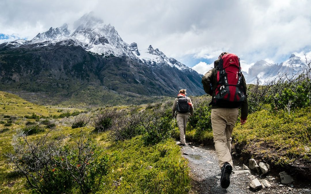 two person walking towards mountain covered with snow