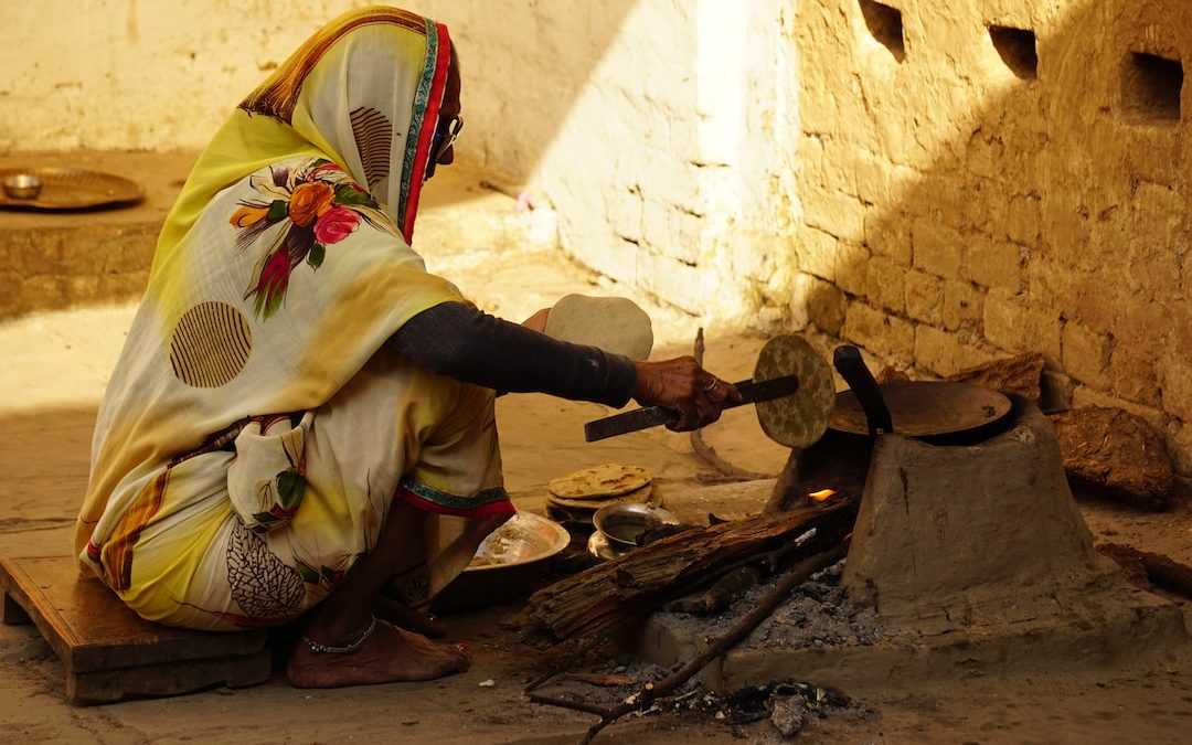 a woman in a yellow and white sari is making food
