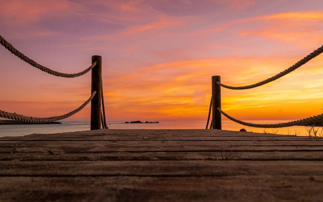 a wooden dock with a sunset in the background