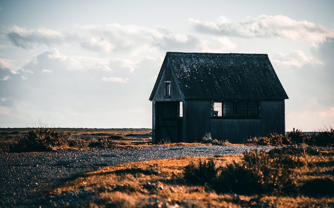 white hut on deserted land under white clouds during daytime