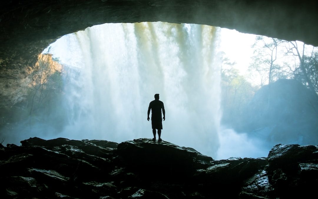 man standing on rock near cave