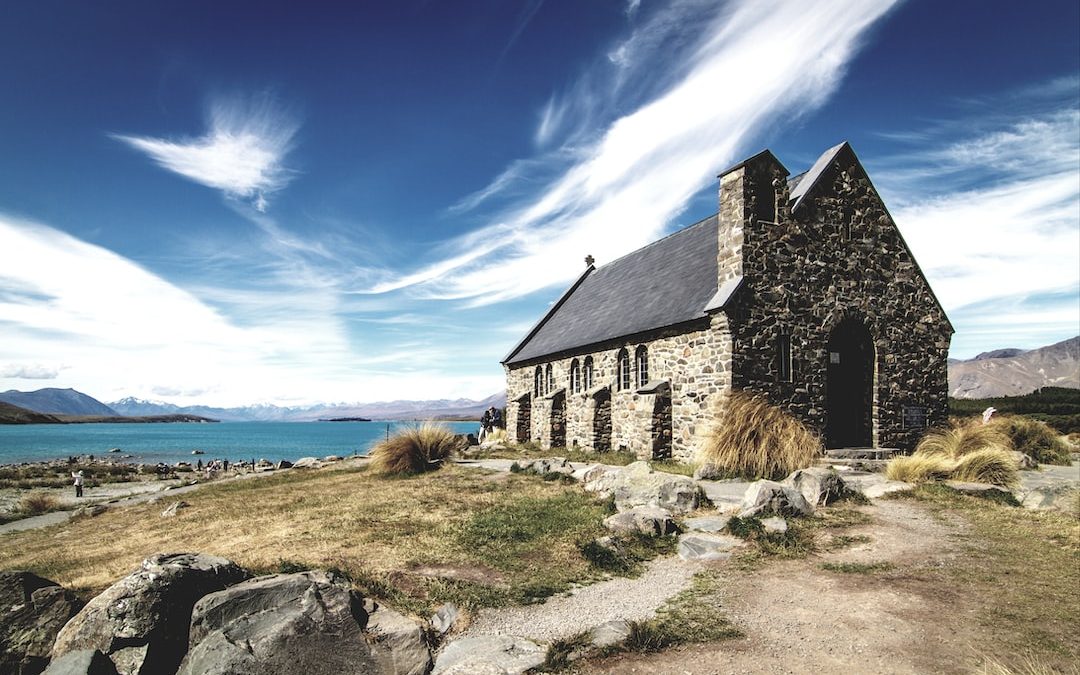 brown and black concrete house in front of body of water