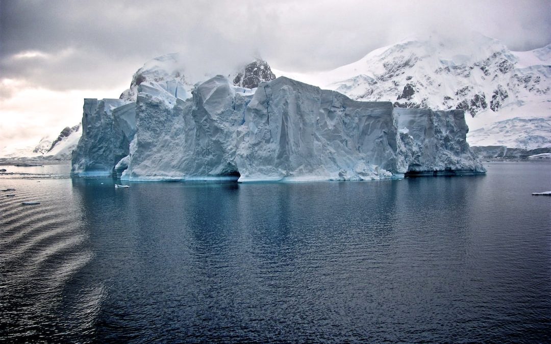 white iceberg near white mountains