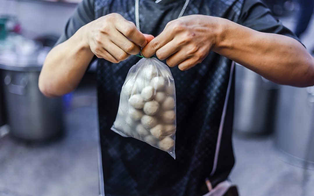 person in black button up shirt holding white and gray textile