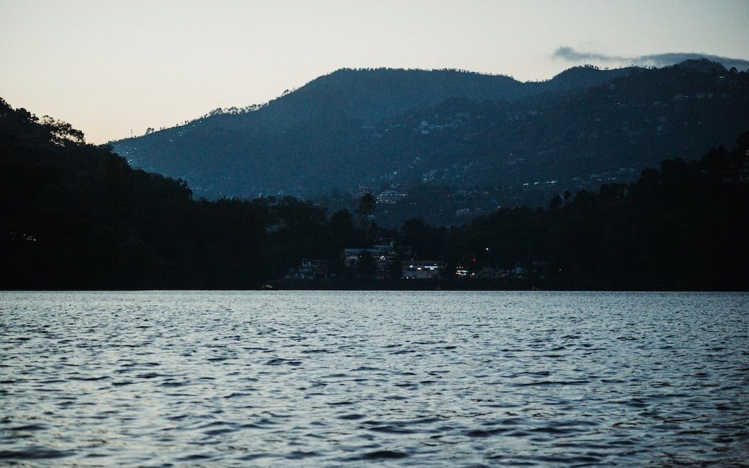 a body of water with a hill in the background