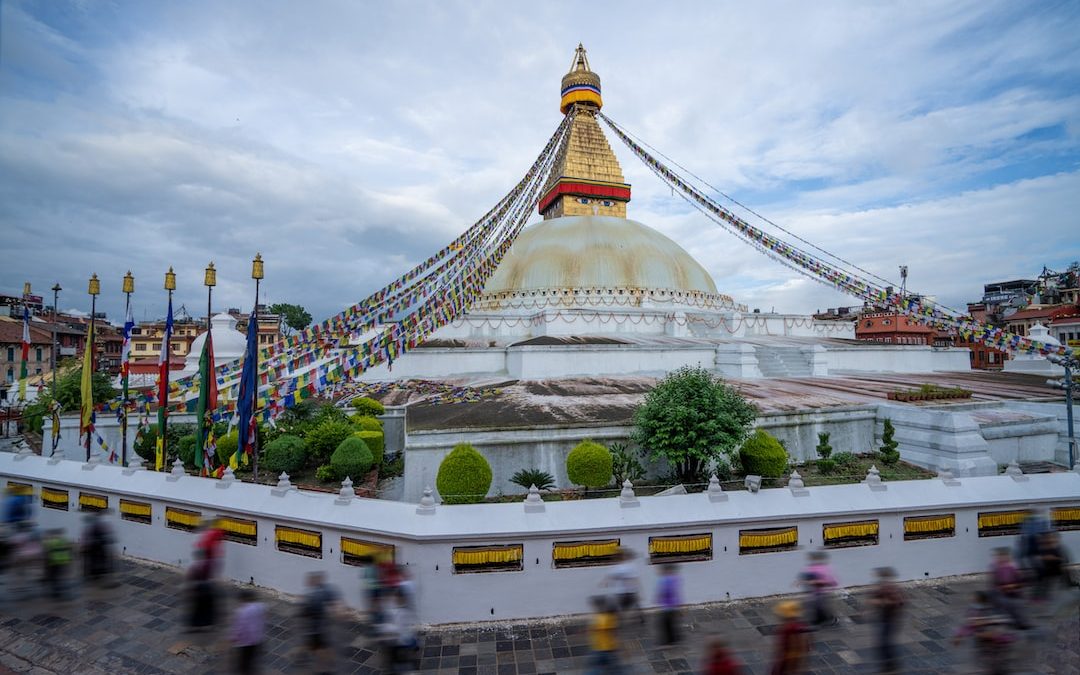 a large building with a domed roof with Boudhanath in the background