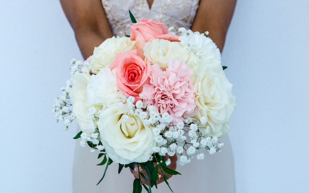 woman wearing white sleeveless wedding dress holding flower bouquet