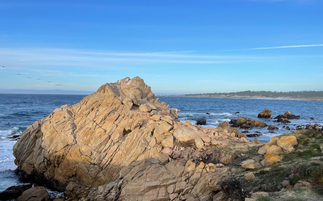 a large rock sitting on top of a beach next to the ocean