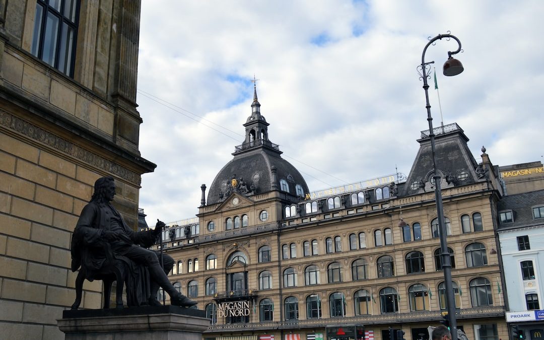 a statue of a man sitting on a bench in front of a building