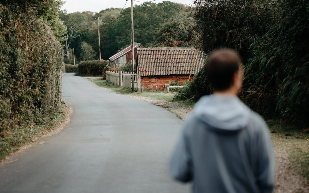 a person walking down a road with a house in the background