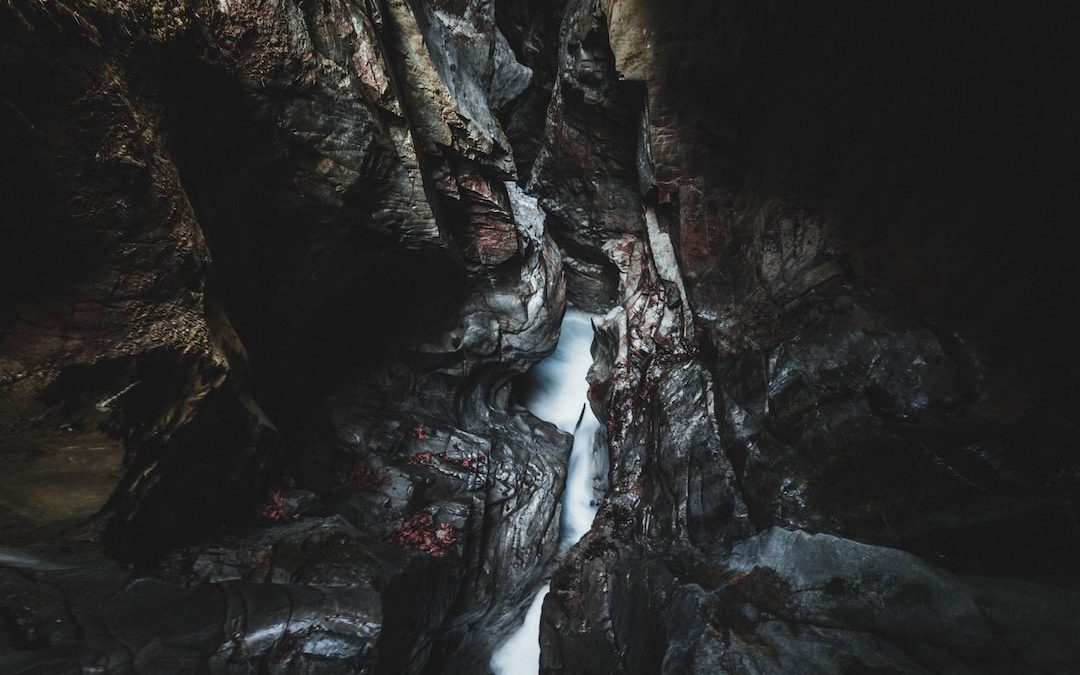 water falls between brown rocky mountain during daytime