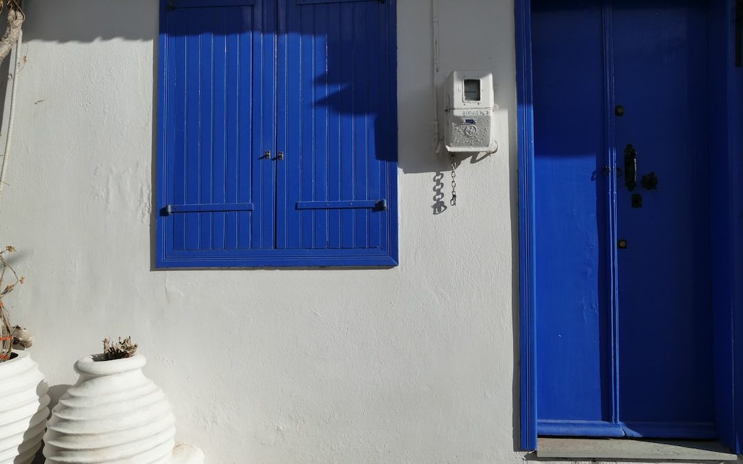 a white building with blue shutters and a phone