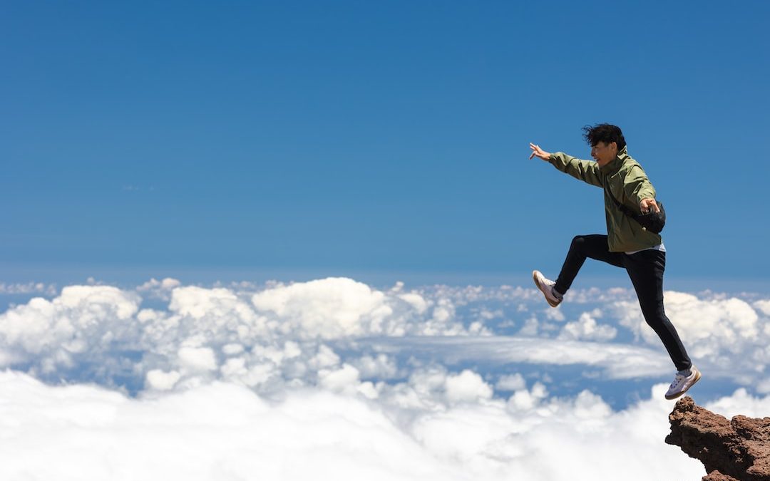 a man jumping off a cliff into the sky