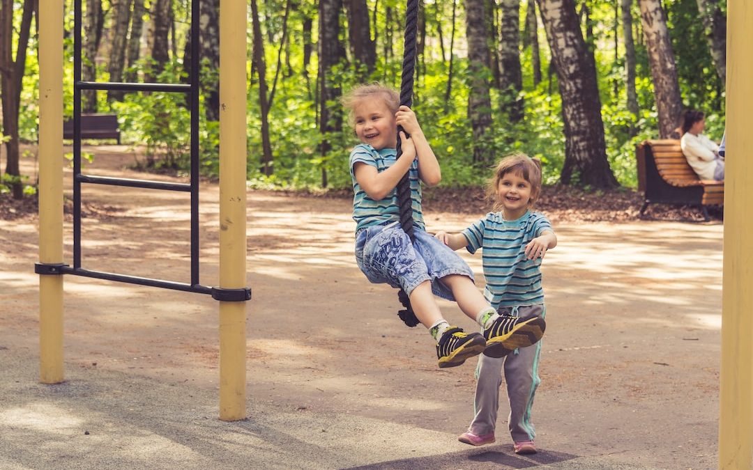 2 boys sitting on swing during daytime