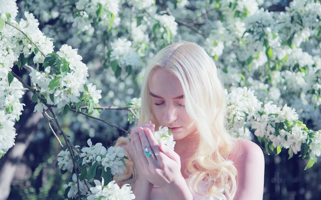 woman smelling flower during daytime