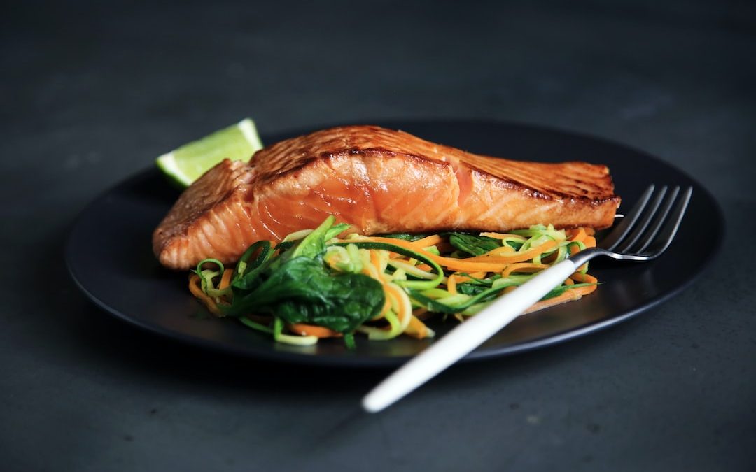 grilled fish, cooked vegetables, and fork on plate