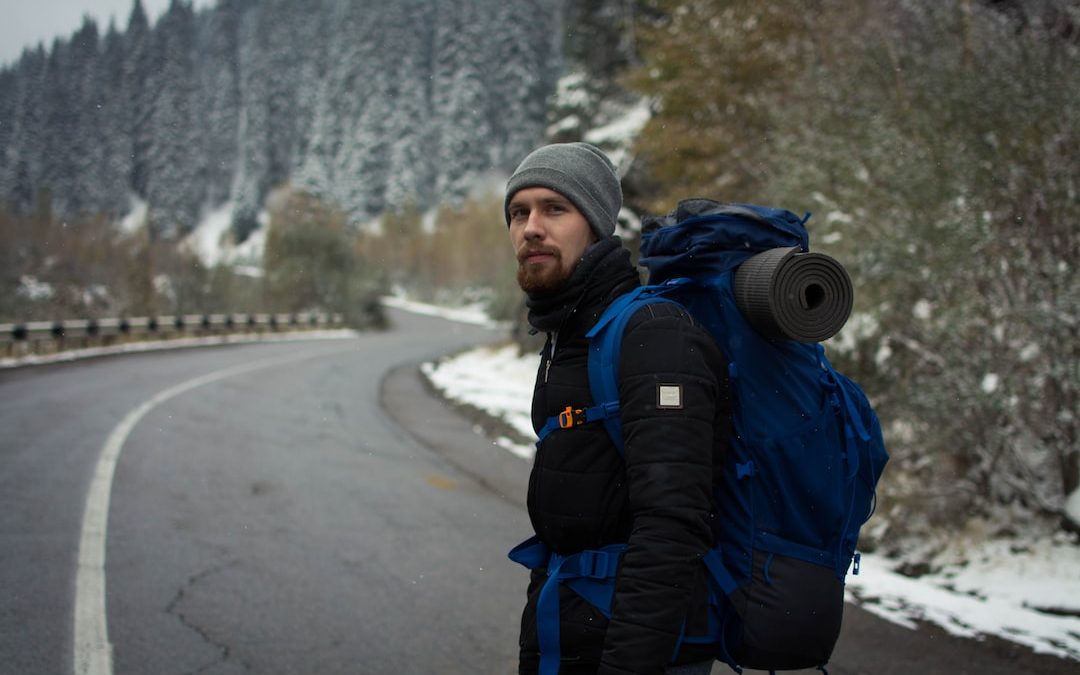a man with a backpack standing on the side of a road