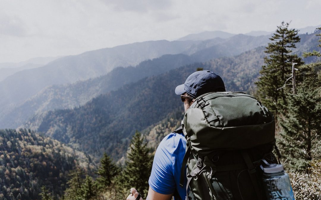 man standing on top of mountain with backpack