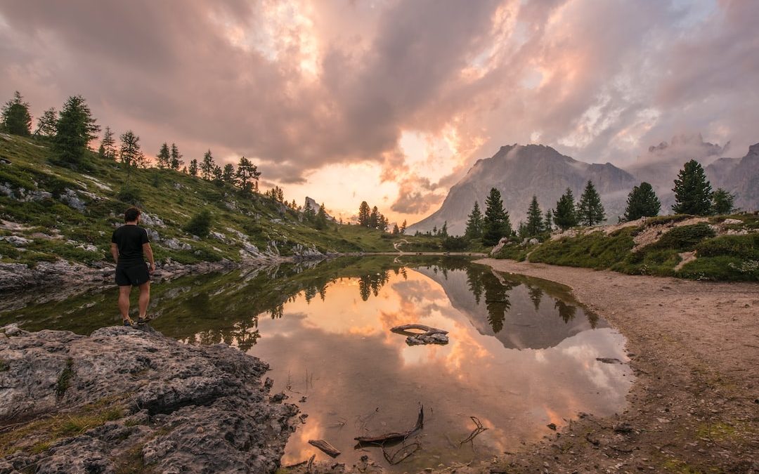 man stands on rock beside body of water during day